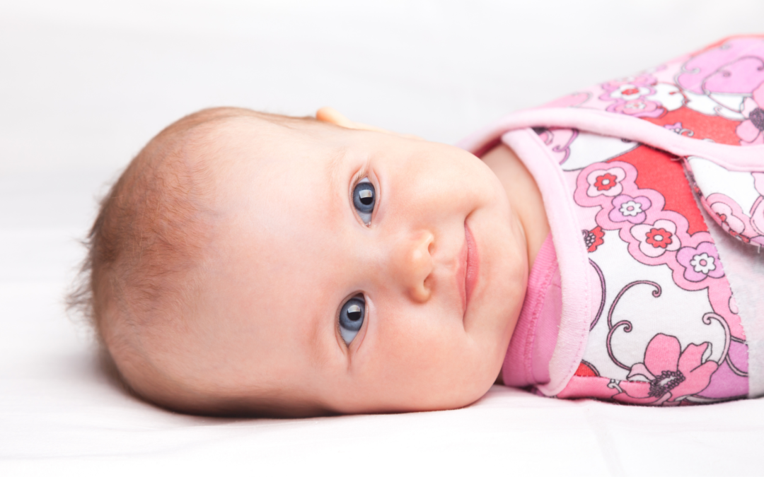 Happy baby wrapped in a pink swaddle